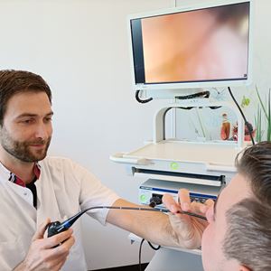  KNO-arts Michel van Hooren bekijkt via de neus met een minuscuul cameraatje de stembanden op een beeldscherm