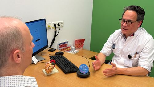 Cardioloog Bart Driesen in gesprek met patiënt, digitale assistent Bo luistert mee Cardioloog Bart Driesen In Gesprek Met Patiënt, Digitale Assistent Bo Luistert Mee