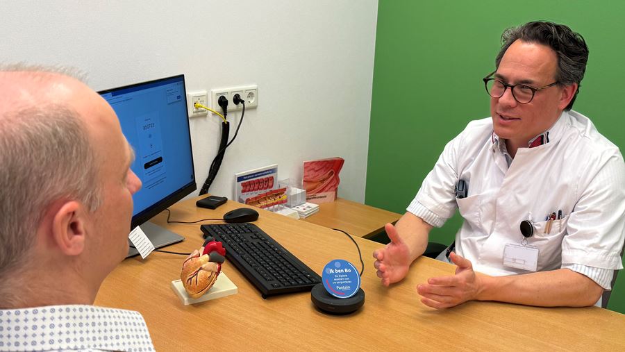 Cardioloog Bart Driesen in gesprek met patiënt, digitale assistent Bo luistert mee Cardioloog Bart Driesen in gesprek met patiënt, digitale assistent Bo luistert mee