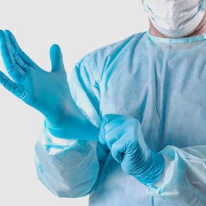 Man in beschermende kleding trekt medische handschoenen aan Uitgelicht afbeelding